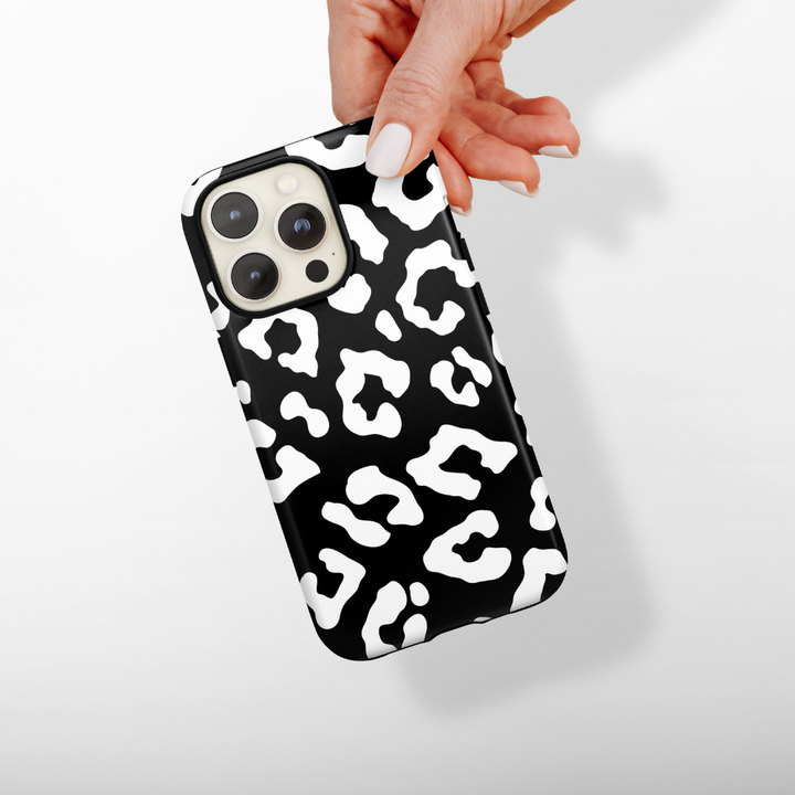 Hand holds a smartphone upright against a plain white background, showcasing the Cocopup London Tough Phone Case - Black Leopard with three rear camera lenses for perfect shots.