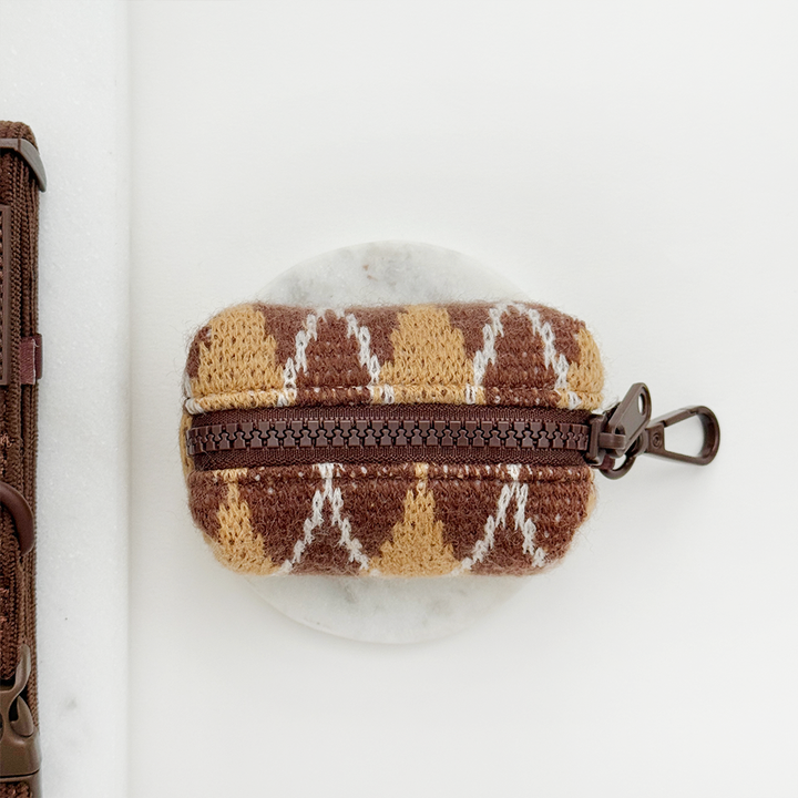 Poop bag holder to hold unused dog poo bags, in a brown, white and tan argyle pattern.