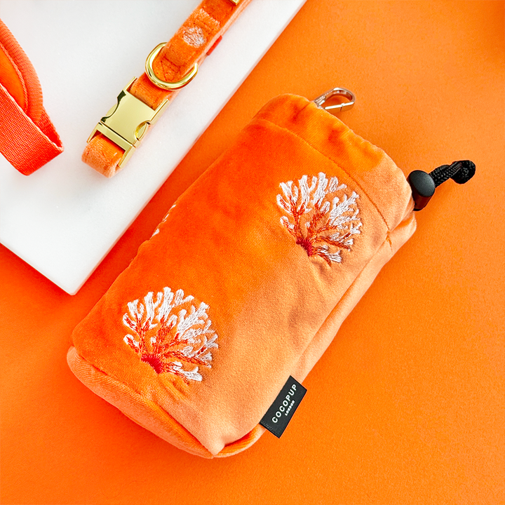 Coral velvet drawstring treat pouch by Cocopup London next to a matching collar with a gold buckle.