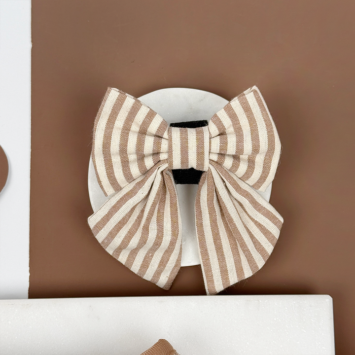 Brown and white striped dog sailor bow tie on a brown background.