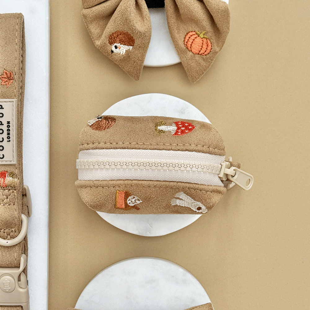 Brown poop bag dispenser, for dog poo bags, with autumnal-themed embroidery of pumpkins, leaves, a coffee cup, and mushrooms.
