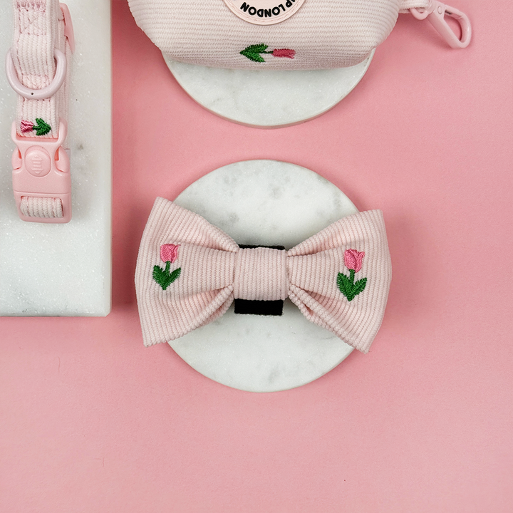 Pink dog bow with floral tulip embroidery on a pink background.