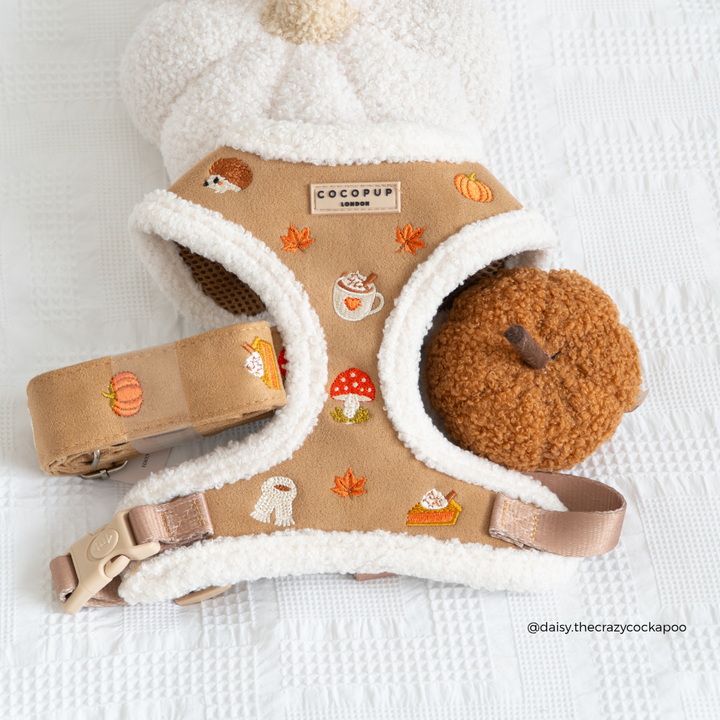 a tan harness with white sherpa trim and cute pumpkin and mushroom illustrations. The brand tag on the harness reads 'cocopup london'
