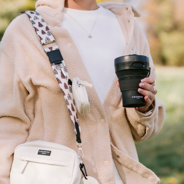 Model holding the Cocopup Black Coffee Cup whilst wearing the Cocopup Black Dog Walking Bag.