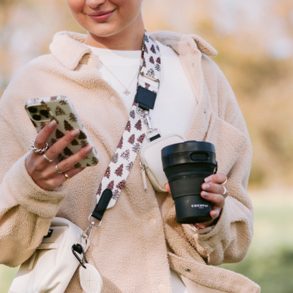 Model holding the Cocopup Black Coffee Cup whilst wearing the Cocopup Black Dog Walking Bag.