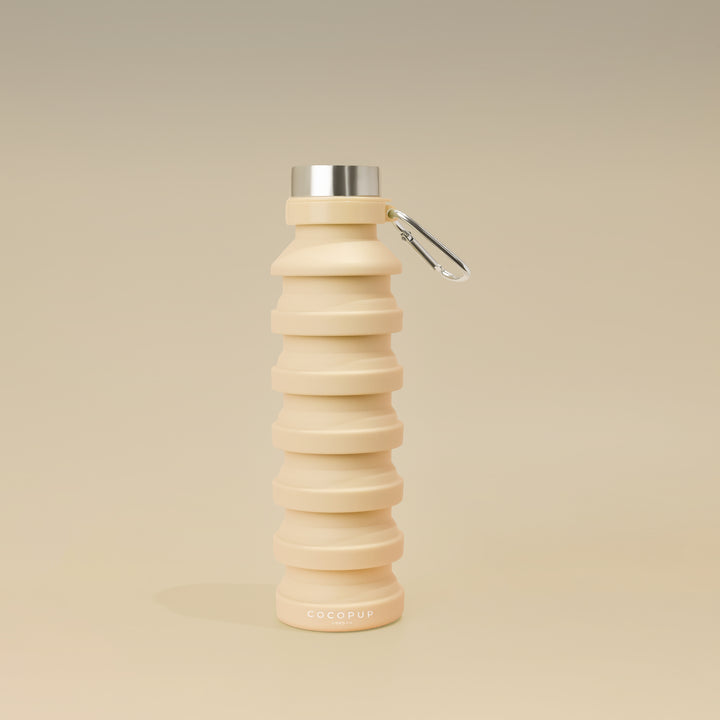 Plain Nude Silicone Collapsible Water Bottle with Cocopup Branding, Stainless Steel Lid and Carabiner Clip.