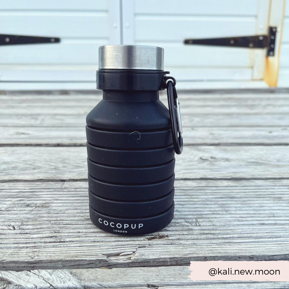 Collapsed view of the Plain Black Silicone Collapsible Water Bottle with Cocopup Branding and Carabiner Clip.